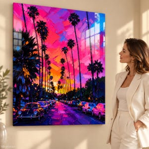 Peut inclure: Une impression d'art mural carrée représentant une scène de rue peinte aux couleurs vives au coucher du soleil. De grands palmiers bordent une route remplie de voitures garées, sous un ciel dramatique aux teintes rose, violet et orange.