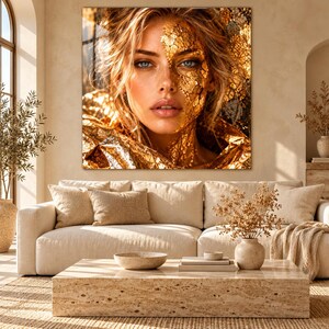 Peut inclure: Une impression d'art mural carr&eacute;e repr&eacute;sentant le portrait d'une personne aux yeux bleus et aux cheveux blonds, avec une partie du visage et du cou recouverte de feuilles d'or textur&eacute;es. L'&oelig;uvre pr&eacute;sente des tons dor&eacute;s m&eacute;talliques.