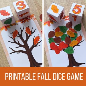 May include: A printable autumn dice game featuring two white paper cubes with numbers and leaf illustrations, and a printed sheet showing a bare tree trunk. The game includes multiple paper leaf cutouts in red, orange, green, and brown colours.