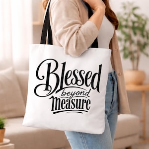 Peut inclure: Un sac fourre-tout blanc avec des anses noires portant le texte noir Blessed beyond measure imprimé dans une police cursive décorative sur le devant. Le sac est fabriqué en tissu et présente une forme rectangulaire avec un fond plat et deux anses.