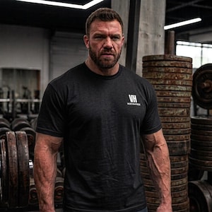 Może przedstawiać: Czarny t-shirt z krótkim rękawem i okrągłym dekoltem, z białym napisem VH oraz VALOR REACTWEAR nadrukowanym na lewej piersi. Odzież wykonana jest z jednokolorowej tkaniny o standardowym kroju, z krótkimi rękawami i prostym, okrągłym dekoltem.