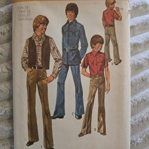 May include: A Simplicity 9482 sewing pattern envelope for teen-boys size 14, chest 32, waist 27. The illustration shows three figures wearing various outfits including a plaid shirt with a vest, a blue button-down shirt with trousers, and a red shirt.