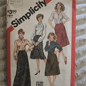 May include: A Simplicity 5748 sewing pattern envelope for size 12, waist 67 cm. The front features illustrations of four different skirt styles paired with various blouses, including a long dark skirt and three knee-length skirts.