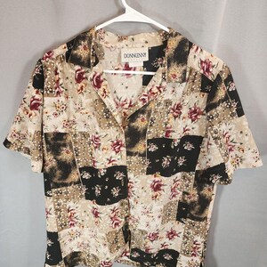 May include: A short-sleeve button-down shirt featuring a patchwork design of floral patterns in shades of beige, black, and deep red. The shirt has a collared neckline and a label at the inner collar that reads DONNKENNY. The fabric has a textured finish.