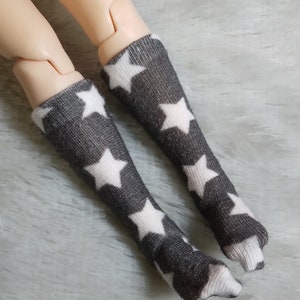 May include: A pair of gray knee-high socks with white stars. The socks are made of a soft, stretchy material and are perfect for everyday wear.