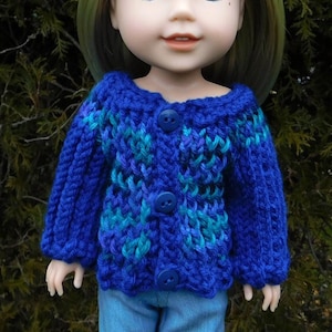 May include: A blue and teal knitted cardigan with blue buttons for a doll. The doll has blonde hair and blue eyes.