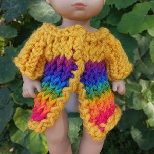 Puede incluir: Un cárdigan de crochet arcoíris con una base amarilla. El cárdigan está abierto en la parte delantera y tiene un corte holgado.