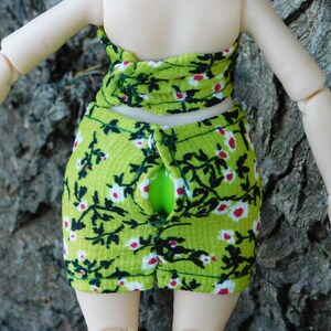 May include: A green and white floral print skirt with a black floral design. The skirt has a zipper down the back.