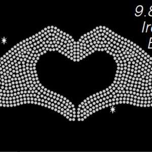 May include: Iron-on rhinestone design of two hands forming a heart shape. The design measures 9.8 inches by 4.5 inches.