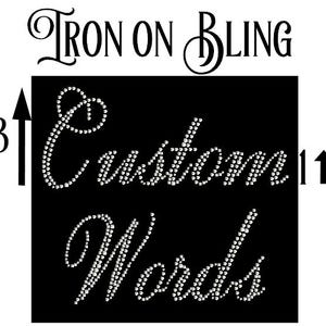 May include: A black rectangular iron-on transfer sheet featuring the text "IRON ON BLING" at the top and the words "Custom Words" in a cursive script formed by small, clear, reflective rhinestones. Two black arrows labeled 3 and 1 are present.