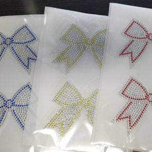 May include: Four sheets of white paper with silver, blue, yellow, and red rhinestone bows. The bows are made of silver rhinestones with colored edges.