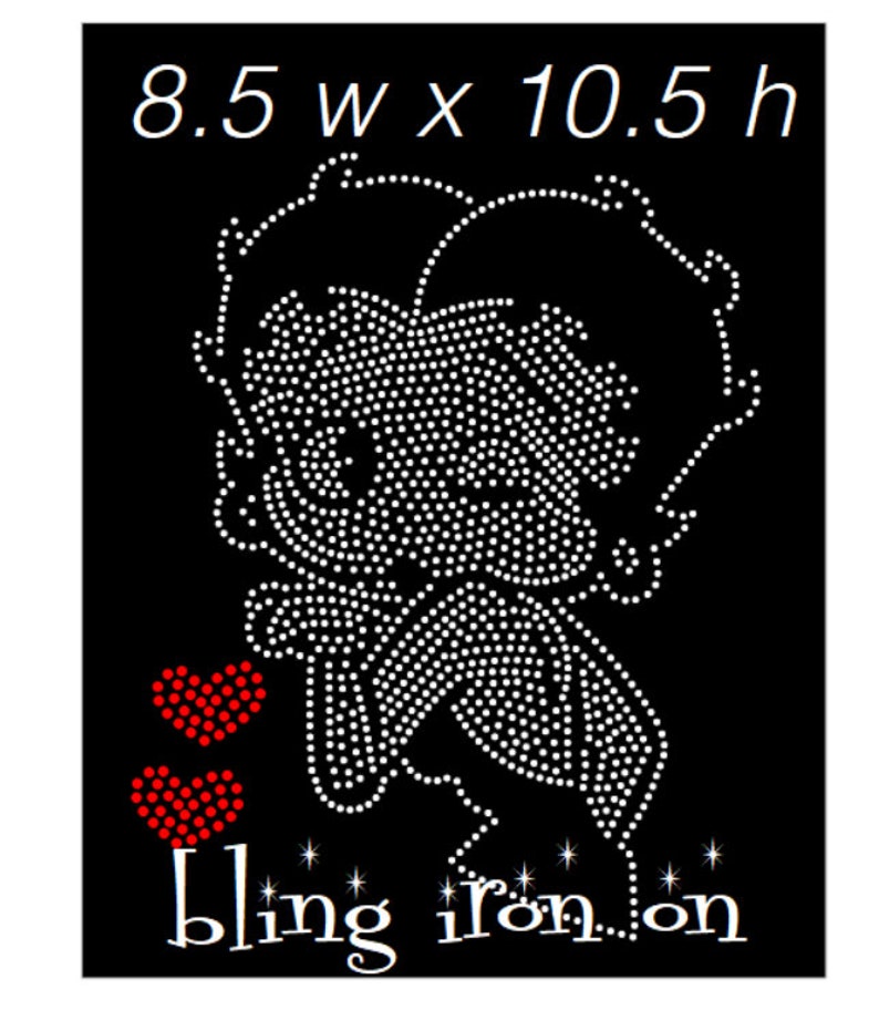 May include: Black iron-on transfer featuring a rhinestone design of a cartoon character, with two red heart accents. The design is 8.5 inches wide by 10.5 inches high, with the words "bling iron on" at the bottom.
