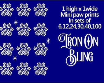 May include: A blue background with nine white rhinestone paw prints. Text reads "1 high x 1 wide Mini paw prints In sets of 6,12,24,30,40,100" and "Iron On Bling" in a decorative font.