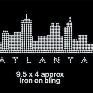 May include: Iron-on bling design of the Atlanta skyline, featuring a white cityscape silhouette on a black background. The design measures approximately 9.5 inches by 4 inches. The text "ATLANTA" is displayed below the skyline.