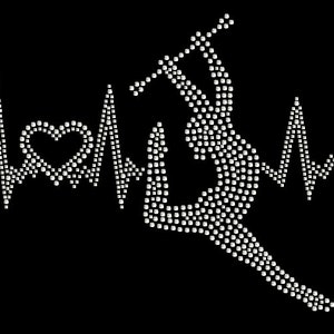 May include: A white rhinestone design of a gymnast performing a handstand on a bar, with a heart and a heartbeat graphic on either side.