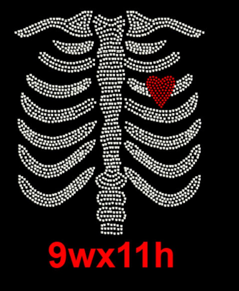 May include: A white rhinestone design of a ribcage with a red rhinestone heart in the center. The design is on a black background and includes the text "9wx11h".