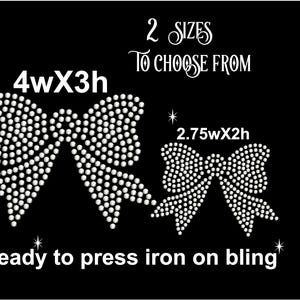 May include: Two sizes of iron-on rhinestone bow designs. The larger bow is 4 inches wide by 3 inches high. The smaller bow is 2.75 inches wide by 2 inches high. Both bows are white and ready to press on.