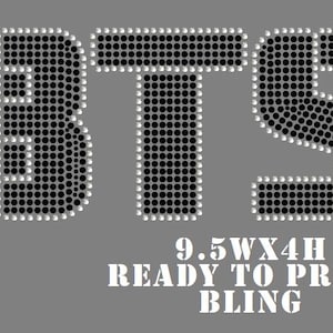 May include: A rhinestone transfer featuring the letters BTS in black stones with a clear stone outline. Below the letters, white text reads 9.5WX4H READY TO PRESS BLING. The design is set against a solid gray background, showcasing the arrangement.