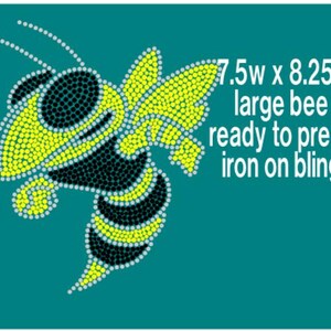 May include: A large bee design made of rhinestones, measuring 7.5 inches wide by 8.25 inches high. The bee is yellow, black, and white, and is ready to be ironed onto fabric.