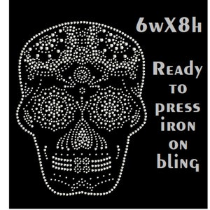 May include: A white rhinestone skull design, 6 inches wide by 8 inches high, ready to be ironed on to fabric. The design is made of small white rhinestones.