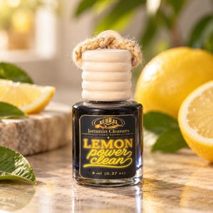 Peut inclure: Un petit flacon en verre avec un bouchon en bois clair et une cordelette tressée. L'étiquette noire porte le texte Jammin Cleaners, LEMON power clean et 8 ml. Le flacon contient un liquide sombre et est surmonté d'un couvercle en bois rainuré.