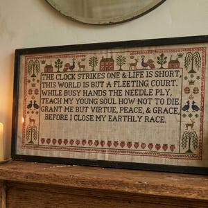 Può includere: Un sampler rettangolare incorniciato con testo ricamato in marrone scuro su uno sfondo di tessuto beige chiaro. Il testo recita: THE CLOCK STRIKES ONE & LIFE IS SHORT, THIS WORLD IS BUT A FLEETING COURT. WHILE BUSY HANDS THE NEEDLE PLY, TEACH MY YOUNG SOUL HOW NOT TO DIE. GRANT ME BUT VIRTUE, PEACE, & GRACE, BEFORE I CLOSE MY EARTHLY RACE.