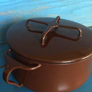May include: A brown enamelled cast iron pot with a lid and two handles. The lid has a metal handle in the shape of an X.