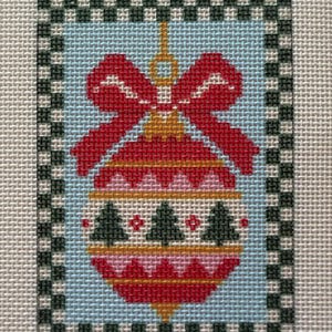May include: A needlepoint canvas featuring a central Christmas ornament design with a red bow, gold cap, and horizontal bands of red, pink, and white. The ornament displays dark green pine tree silhouettes and is framed by a black and white checkered border on a light blue background.