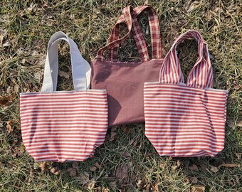 May include: Three striped tote bags with red and white stripes. The bags are made of fabric and have fabric handles.