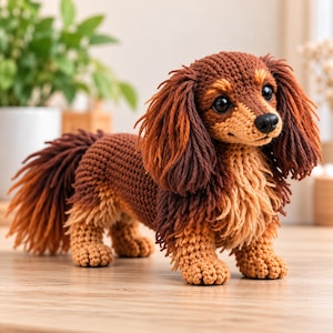 May include: A crocheted dachshund toy featuring a dark brown body with lighter tan accents on the chest and face. The figure has long, textured ears, a bushy tail, and black plastic eyes with a small black nose, crafted with yarn.