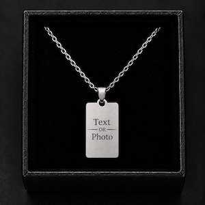 May include: A silver-coloured rectangular dog tag pendant hangs from a matching metal chain. The pendant features the engraved text "Text OR Photo" with horizontal lines above and below the word "OR". The necklace is presented in a black box.