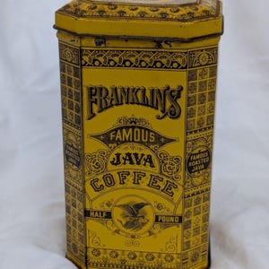 Puede incluir: Una lata metálica hexagonal amarilla con patrones decorativos negros y el texto Franklin's Famous Java Coffee y Half Pound. El recipiente cuenta con una tapa con un diseño amarillo y negro a juego y una ilustración de un águila al frente.