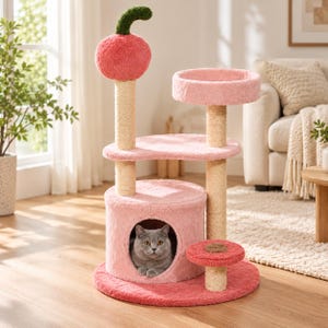 Può includere: Un tiragraffi a più livelli con una ciliegia in peluche rosa sulla sommità, una base circolare, pali rivestiti in sisal e una cuccia chiusa. Un gatto grigio riposa all'interno. La struttura include diverse piattaforme rivestite in morbido tessuto rosa.