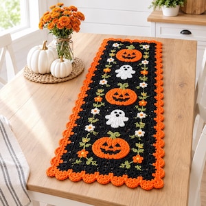 Peut inclure: Un chemin de table en crochet rectangulaire avec un fond noir, alternant des citrouilles d'Halloween orange et des fantômes blancs. Le chemin est bordé d'un bord orange festonné et orné de petites vignes florales blanches et orange.