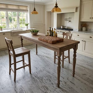 May include: A rectangular wooden kitchen island table with turned legs, accompanied by two matching wooden bar stools. A large square wooden cutting board sits on the tabletop, alongside several glass bottles and a bowl of green herbs.