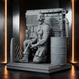 May include: A monochromatic gray resin figurine of a tactical operative in a kneeling position, wearing night-vision goggles and gear. The figure is set against a detailed backdrop featuring a brick wall, a metal barrel, and industrial piping.