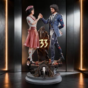 Può includere: Una statuetta dettagliata con due figure su una base rocciosa con il numero 33 al centro. Una figura indossa un top bianco, una gonna rosa e un basco, mentre l'altra indossa un abito blu. Petali rosa sono sparsi attorno alle figure.