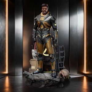 Könnte beinhalten: Eine detaillierte Sammlerfigur eines bärtigen Mannes in einem schwarz-goldenen High-Tech-Panzeranzug mit einem Lambda-Symbol auf der Brust. Die Figur trägt eine Brille, hält ein rotes Brecheisen und steht auf einem felsigen Sockel.