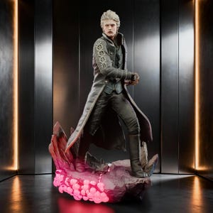 May include: A detailed collectible figurine of a silver-haired character wearing a long grey coat with intricate sleeve embroidery, a dark vest, and black trousers. The figure stands on a jagged, rocky base illuminated by glowing pink light.