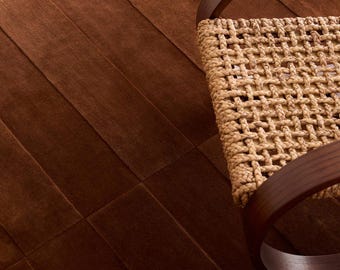 May include: A chair with a dark brown curved wooden frame and a woven light tan rope seat. The chair is positioned on a floor made of large, rectangular, dark brown tiles with a smooth, matte finish and visible seams.