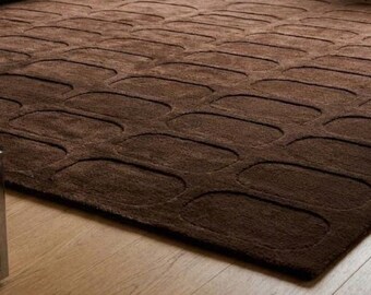 May include: A dark brown area rug featuring a repeating pattern of raised, rounded rectangular shapes. The rug has a textured, plush surface with a consistent deep brown color throughout, creating a uniform look across the entire floor covering.