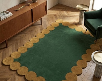 May include: A rectangular area rug featuring a solid dark green center panel surrounded by a border of interconnected mustard yellow circles. The rug has a tufted texture and is positioned on a wooden floor with a herringbone pattern.