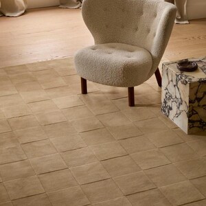 Modern toffee brown geometric rug featuring a raised checkerboard pattern, styled beneath a wooden desk in a sophisticated home office.