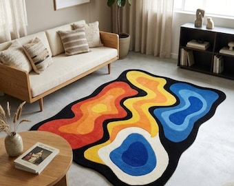 May include: An area rug with an irregular, organic shape featuring a black background and layered, wavy patterns in vibrant shades of red, orange, yellow, cream, and blue, creating a bold, multi-colored, abstract topographic design.