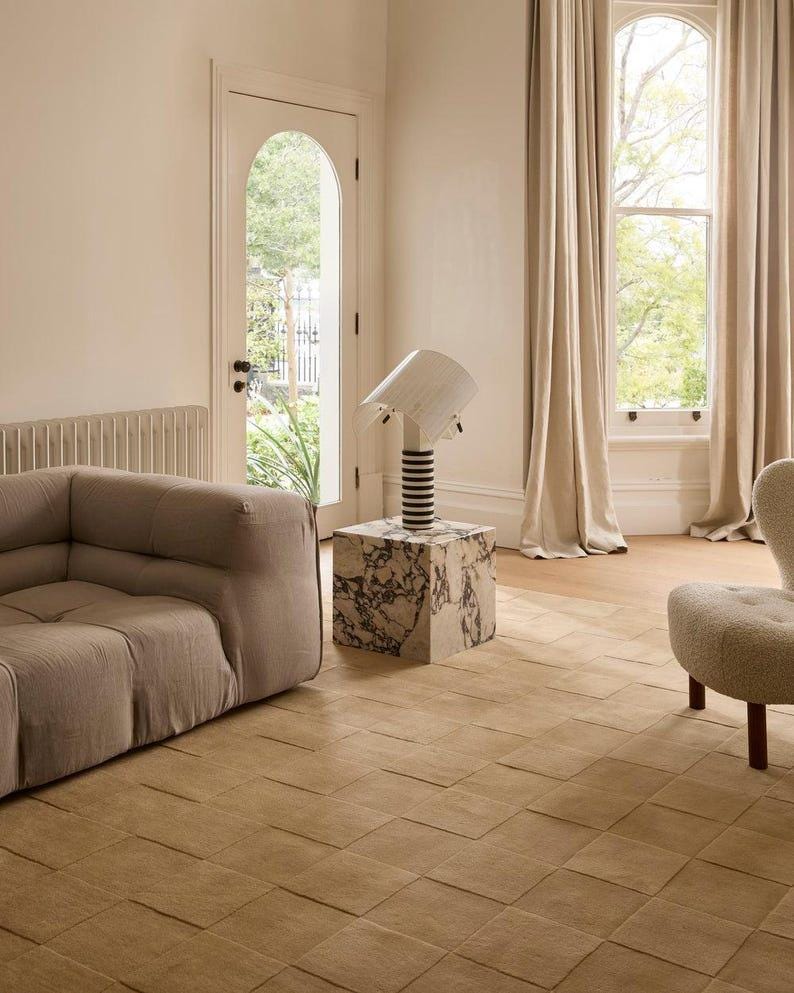Toffee brown textured area rug with a raised square checkerboard design styled in a modern living room with a neutral sofa and elegant furniture.