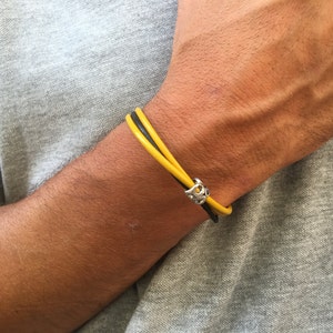 May include: A yellow and black leather bracelet with a silver clasp.