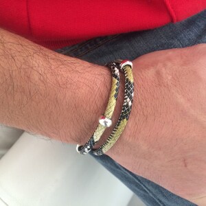 May include: A double-wrap bracelet with a black, white, and yellow snakeskin pattern. The bracelet has silver metal accents.