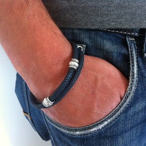 May include: A black leather bracelet with silver beads. The bracelet is worn on a person's wrist.