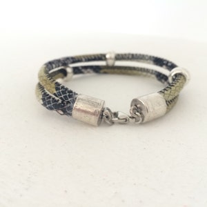 May include: A double-layered bracelet with a black and green patterned fabric and silver metal accents.