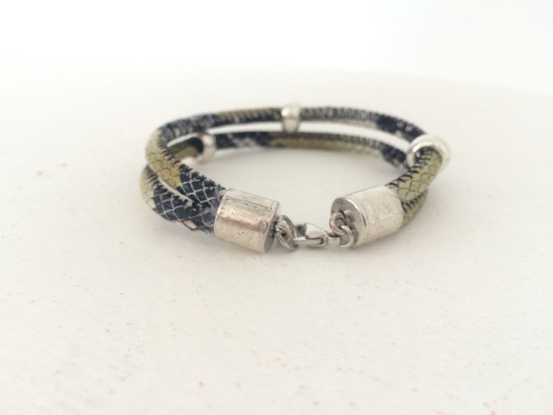 May include: A double-layered bracelet with a black and green patterned fabric and silver metal accents.